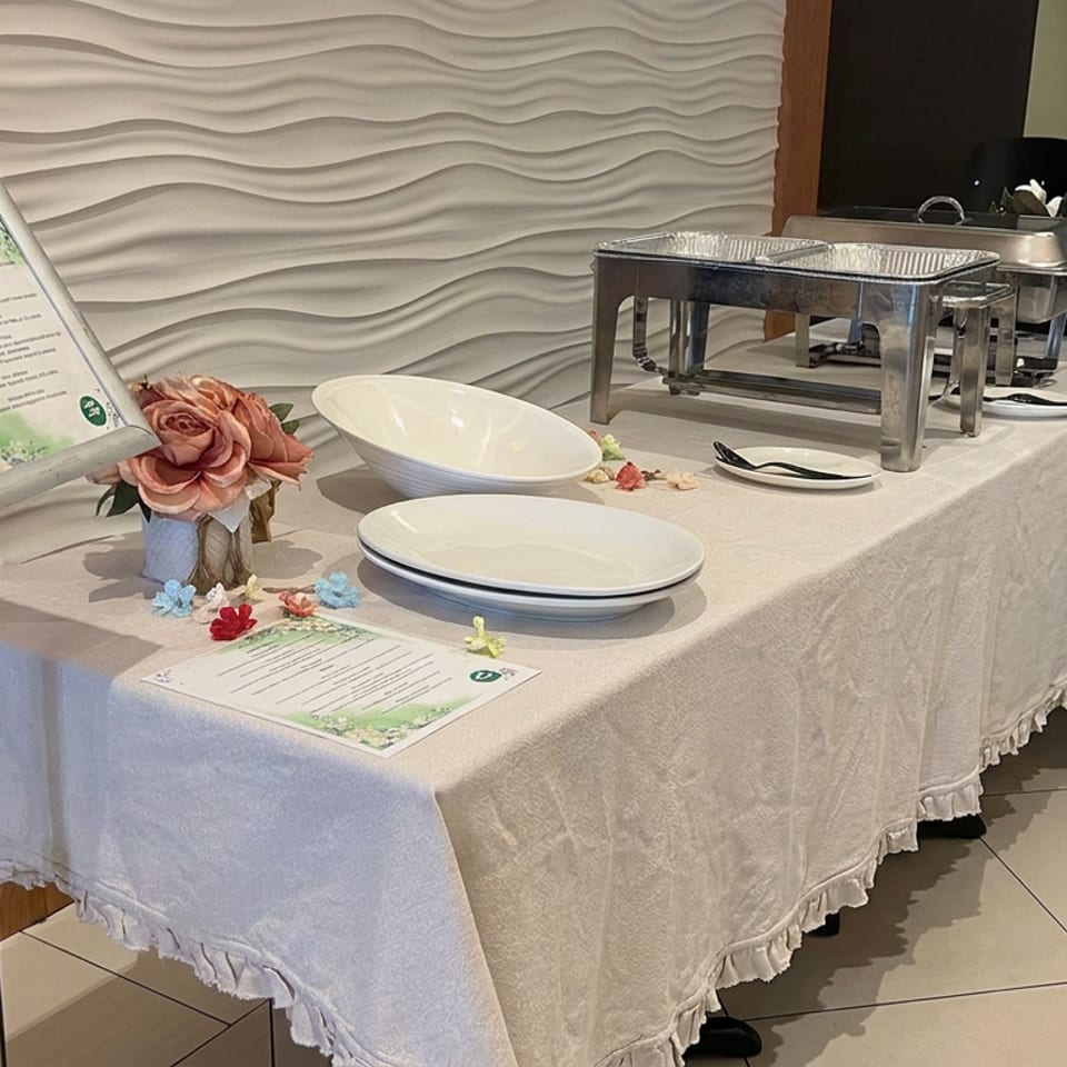 Elegant restaurant buffet table with white linens, chafing dishes, serving plates, floral centerpiece, and menu displays.